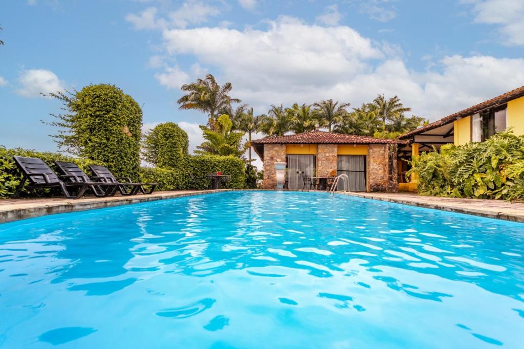 einen Pool mit blauem Wasser vor einem Haus in der Unterkunft Hotel Highlander in Gravatá