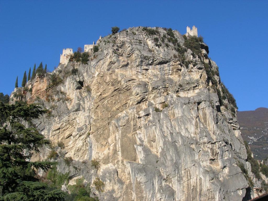 a rocky mountain with trees on top of it at Residenza Alice in Arco