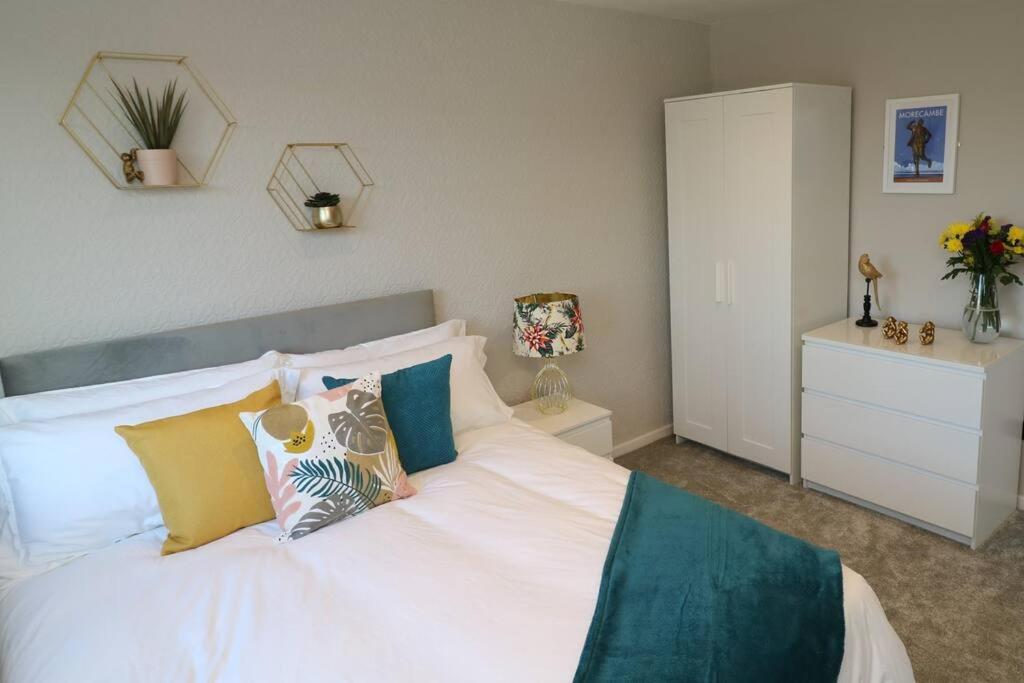 1 dormitorio con cama blanca y almohadas coloridas en Welcoming 2 Bedroom Home with Driveway Parking, en Morecambe