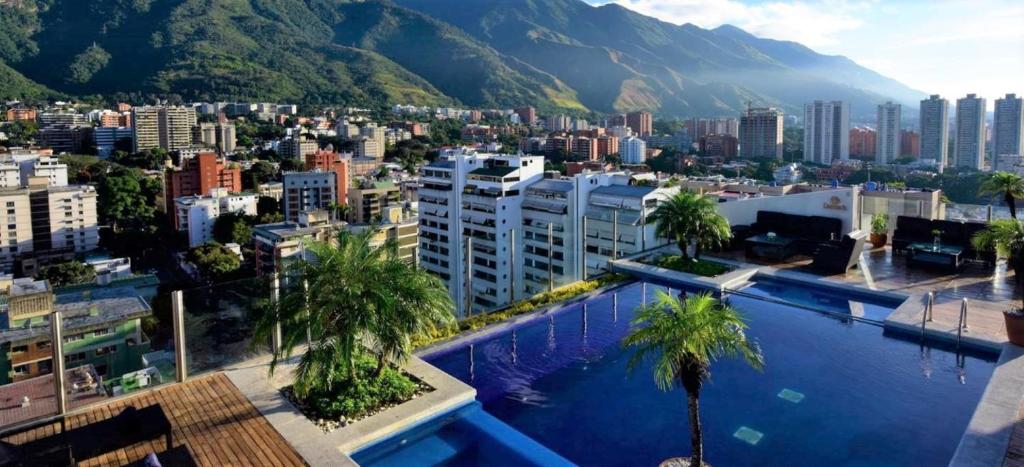 uma grande piscina com palmeiras em frente a uma cidade em Pestana Caracas Premium City & Conference Hotel em Caracas