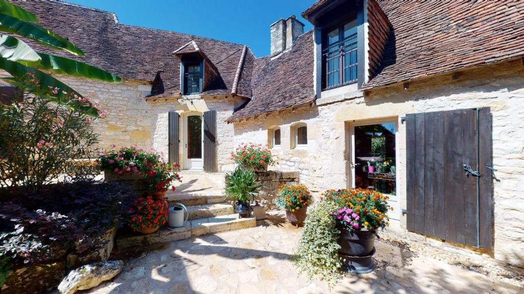 an old stone building with flowers in front of it at Demeure du Vallon - Chambres d'Hôtes de Charme in Azerat