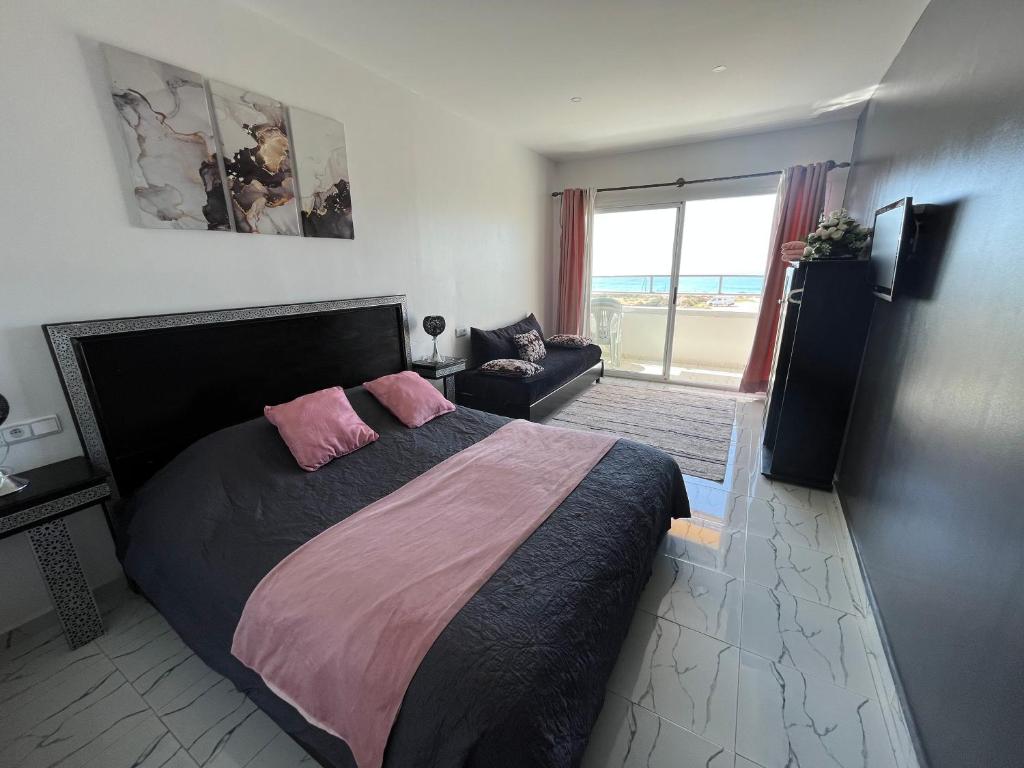 1 dormitorio con 1 cama grande con almohadas rosas en Riad Dar Naima Imsouane, en Imsouane
