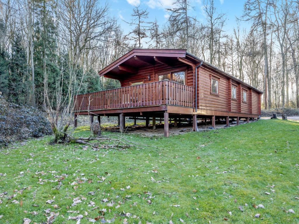 a large wooden cabin in a field of grass at Forest Lodge in Legbourne