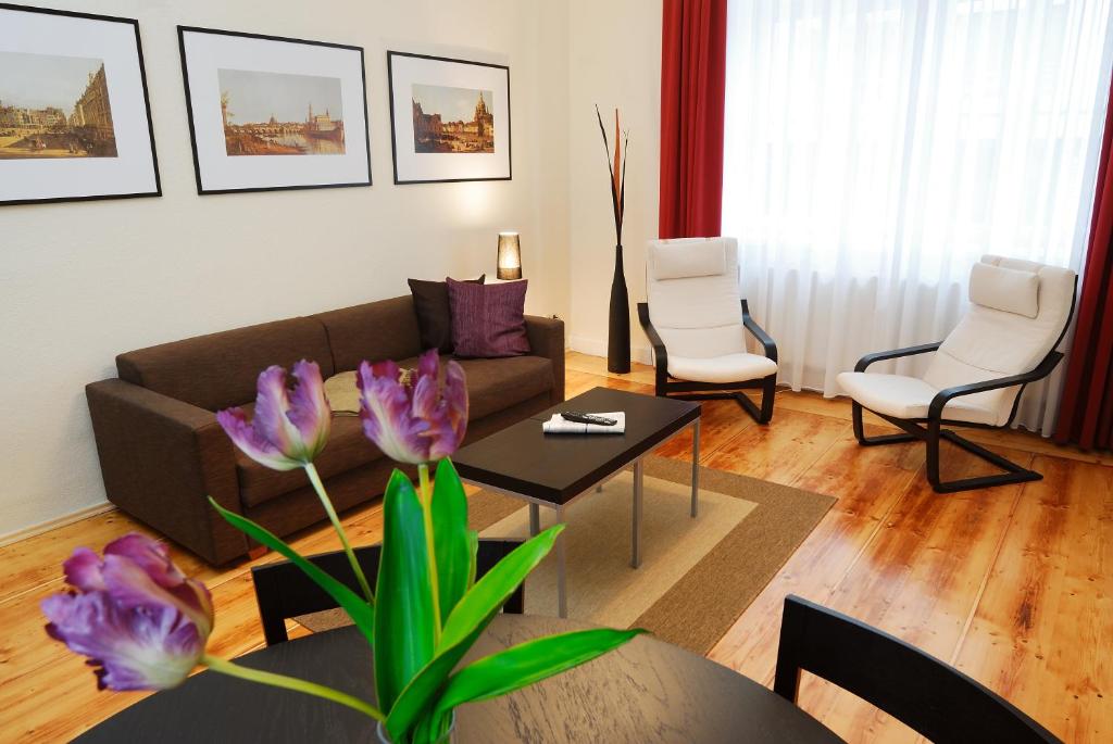 a living room with a couch and a table with purple flowers at Aparthotel am Zwinger in Dresden