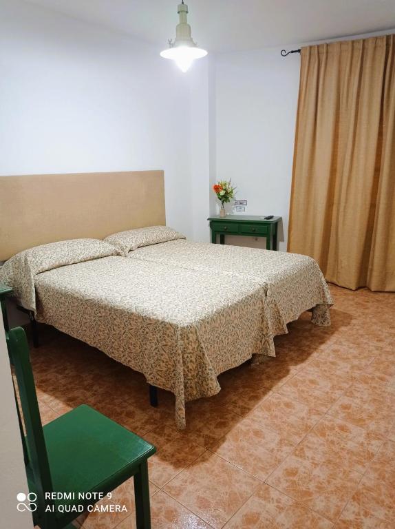 a bedroom with a bed and a green table at Hostal Buena Vista in Vejer de la Frontera