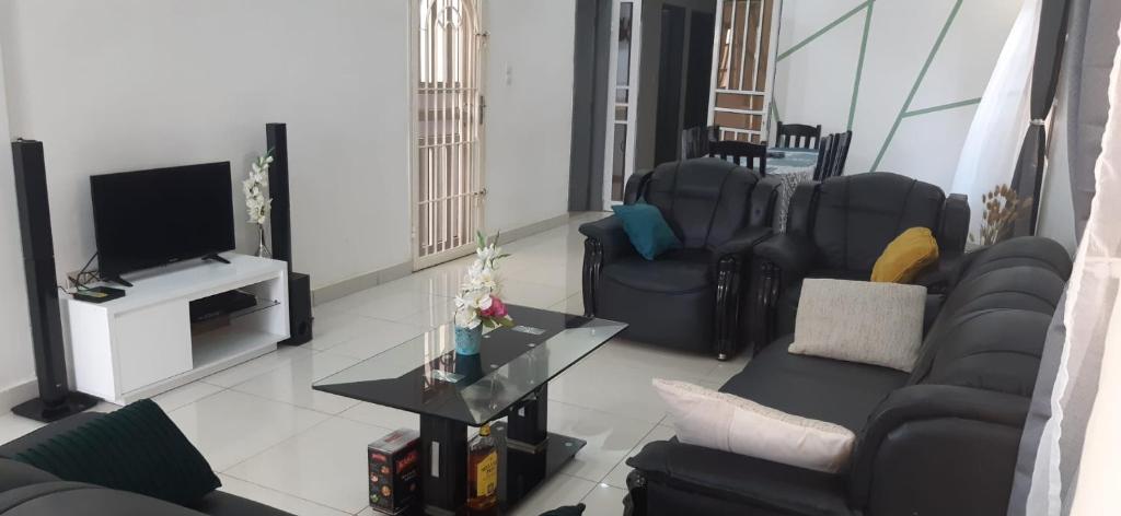 ein Wohnzimmer mit schwarzen Möbeln und einem TV in der Unterkunft Maison individuelle cozy à OUEDO cotonou 