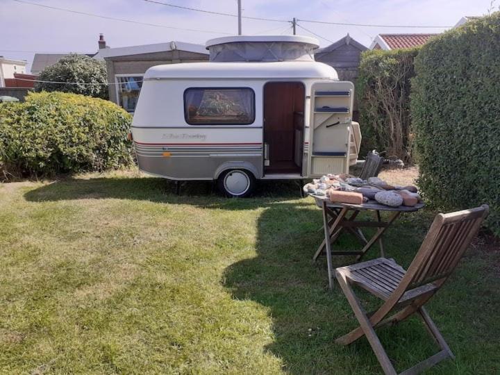 una caravana estacionada en un patio con una mesa y una silla en Sundial Cottage Eriba Caravan, en Norwich