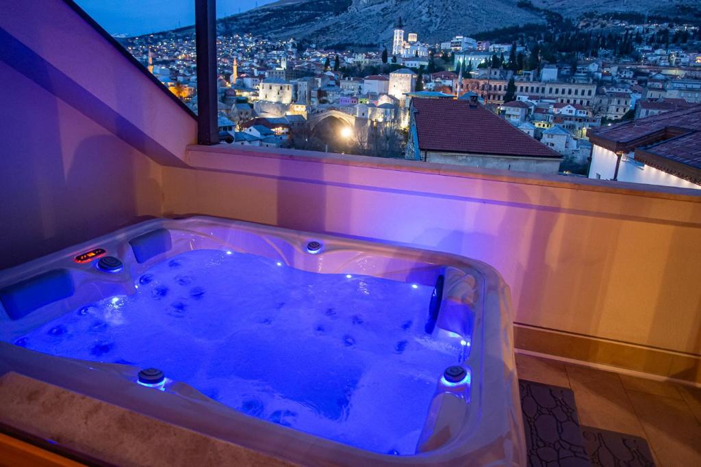 a bath tub in a room with a view of a city at Exclusive Penthouse Old town with sauna and jacuzzi in Mostar
