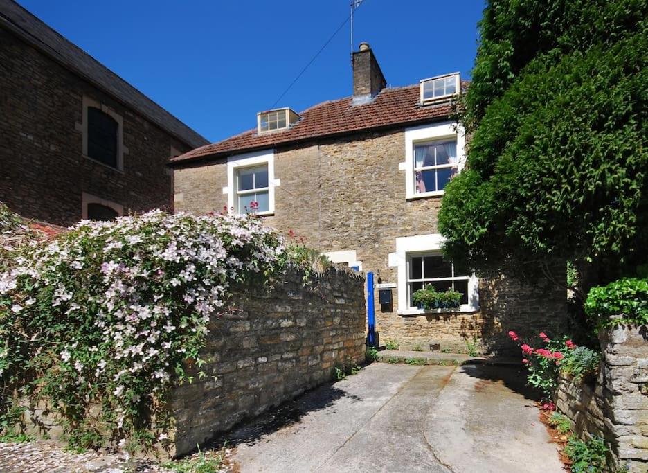 a brick house with a stone wall and flowers at Charming Cottage in the Heart of Frome with parking in Frome