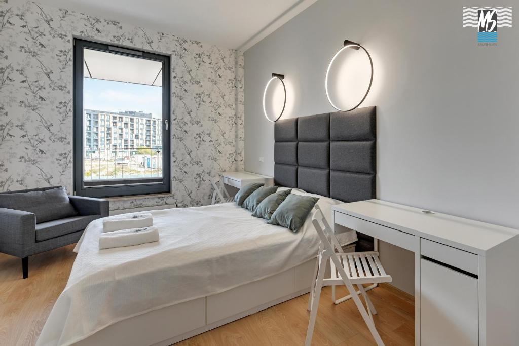 biała sypialnia z łóżkiem i biurkiem w obiekcie MS Apartments Motława I w Gdańsku