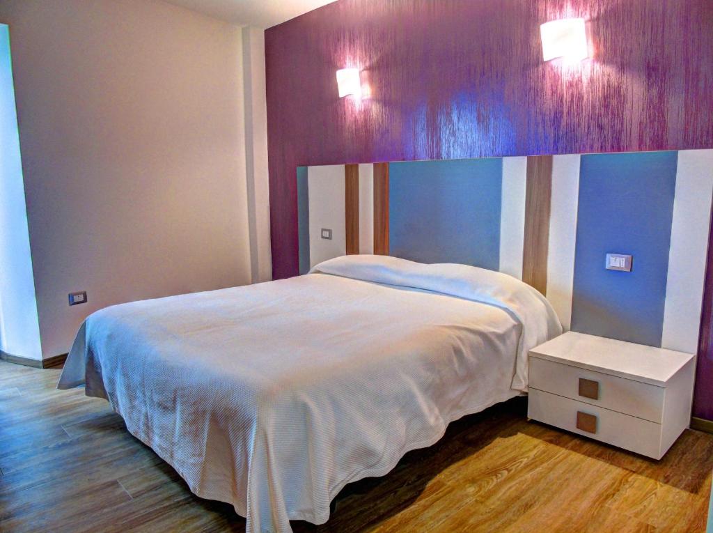 1 dormitorio con cama blanca y pared morada en B&B Il Belvedere Viggiano, en Viggiano