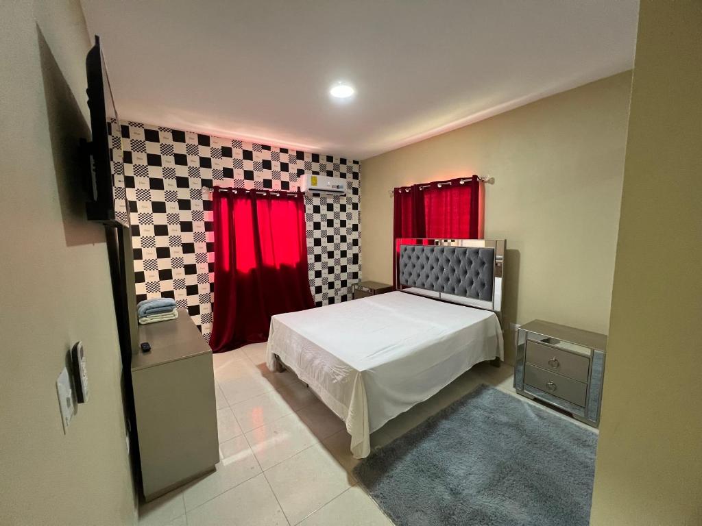1 dormitorio con 1 cama con cortinas rojas en Edificio ramirez, en Baní