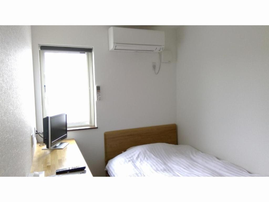 1 dormitorio con 1 cama y escritorio con TV en Minshuku Cress - Vacation STAY 48357v, en Biei