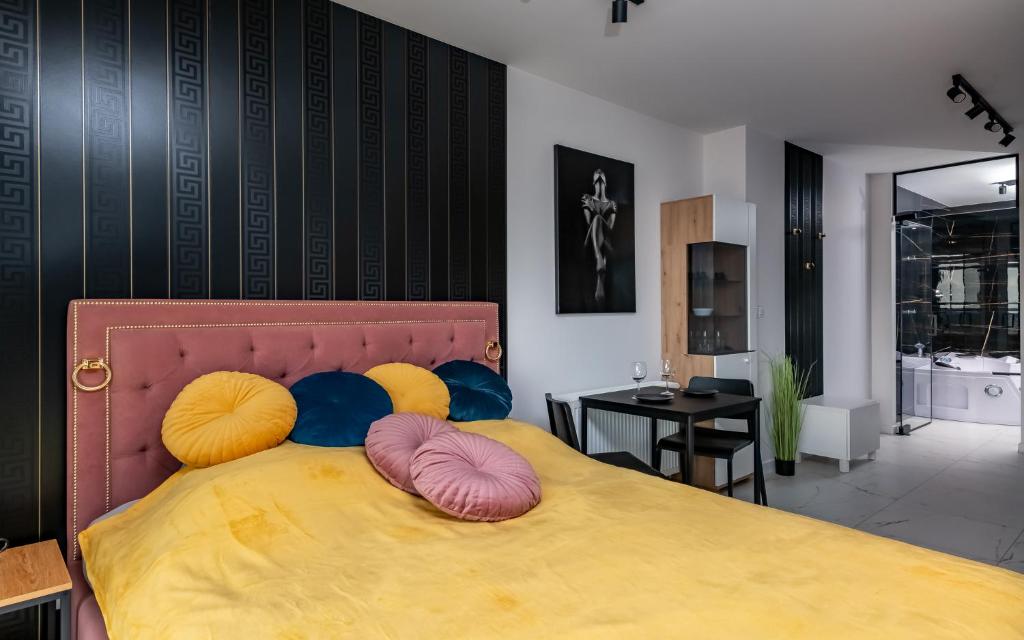 - une chambre avec un grand lit jaune et des oreillers colorés dans l'établissement LoveRoom Panorama Park Jacuzzi, à Białystok