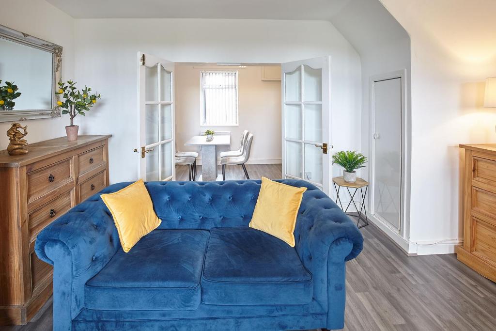 Boosbeck的住宿－Pretty house in the North Yorkshire Moors，客厅配有一张蓝色的沙发,配有一张桌子