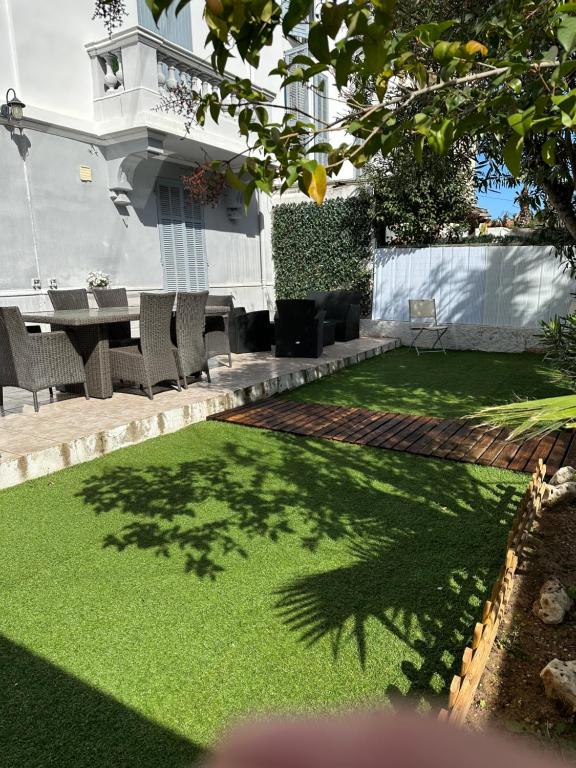 une cour avec de l'herbe verte, une table et des chaises dans l'établissement villa Siana, à Antibes