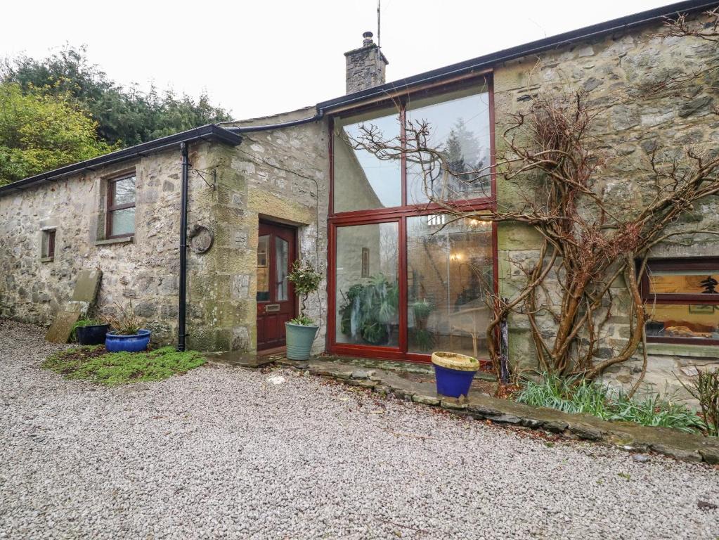 an old stone cottage with a red door and windows at Haworth Barn in Stainforth