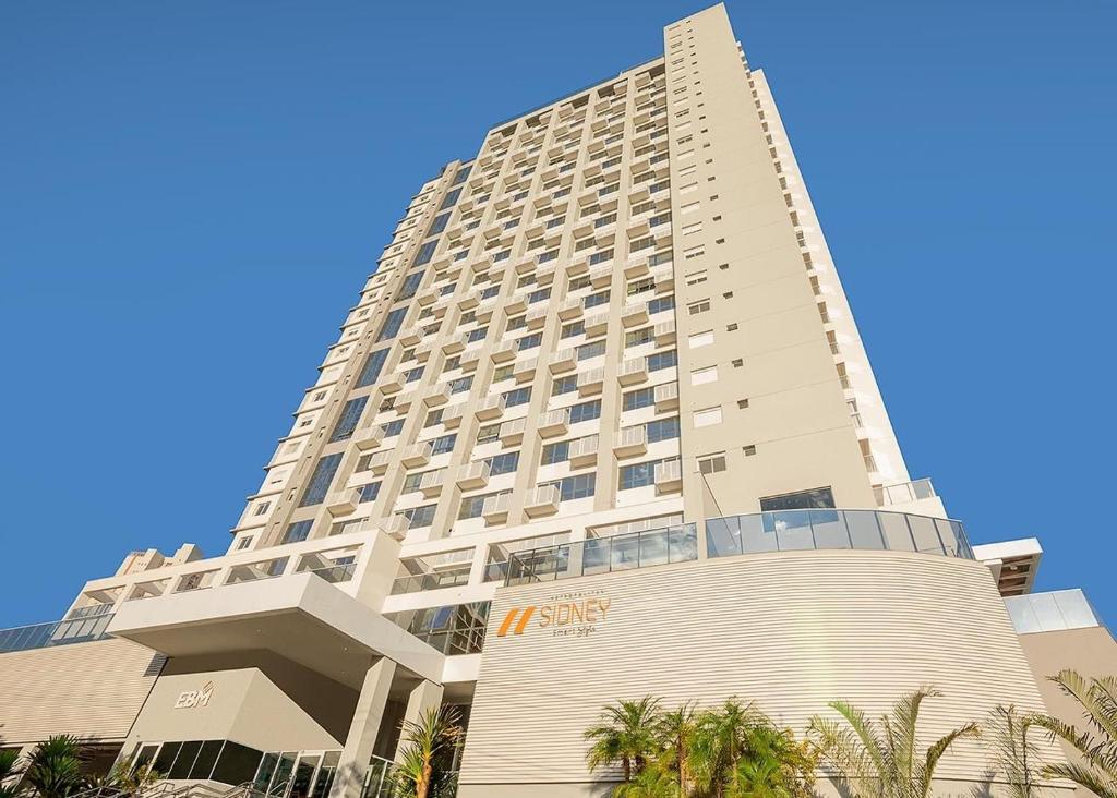 un edificio alto con palmeras delante en Housi - Metropolitan Sidney Smart Style en Goiânia