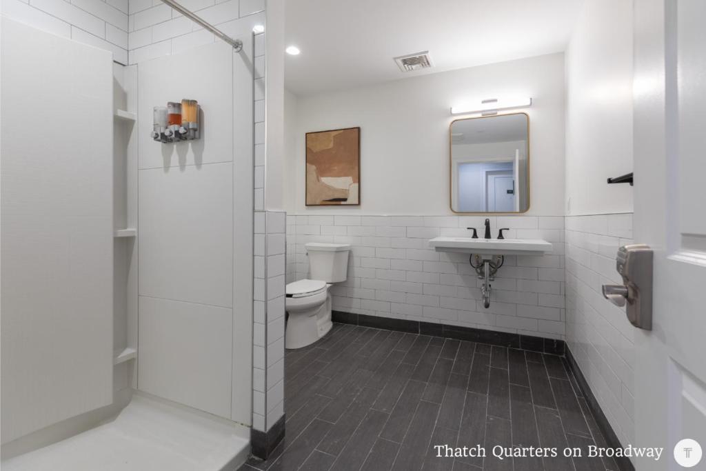 a bathroom with a toilet and a sink and a mirror at West Broadway Quarters by Thatch in Boston