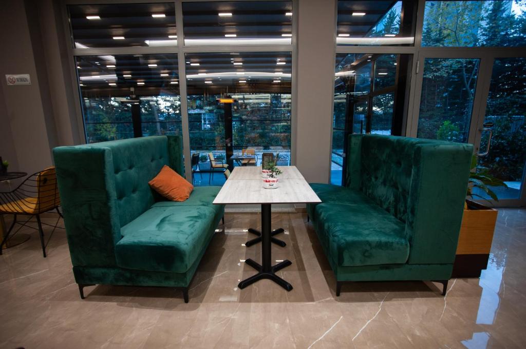 two green chairs and a table in a room with windows at Doanesia Premium Hotel & Spa in Tirana