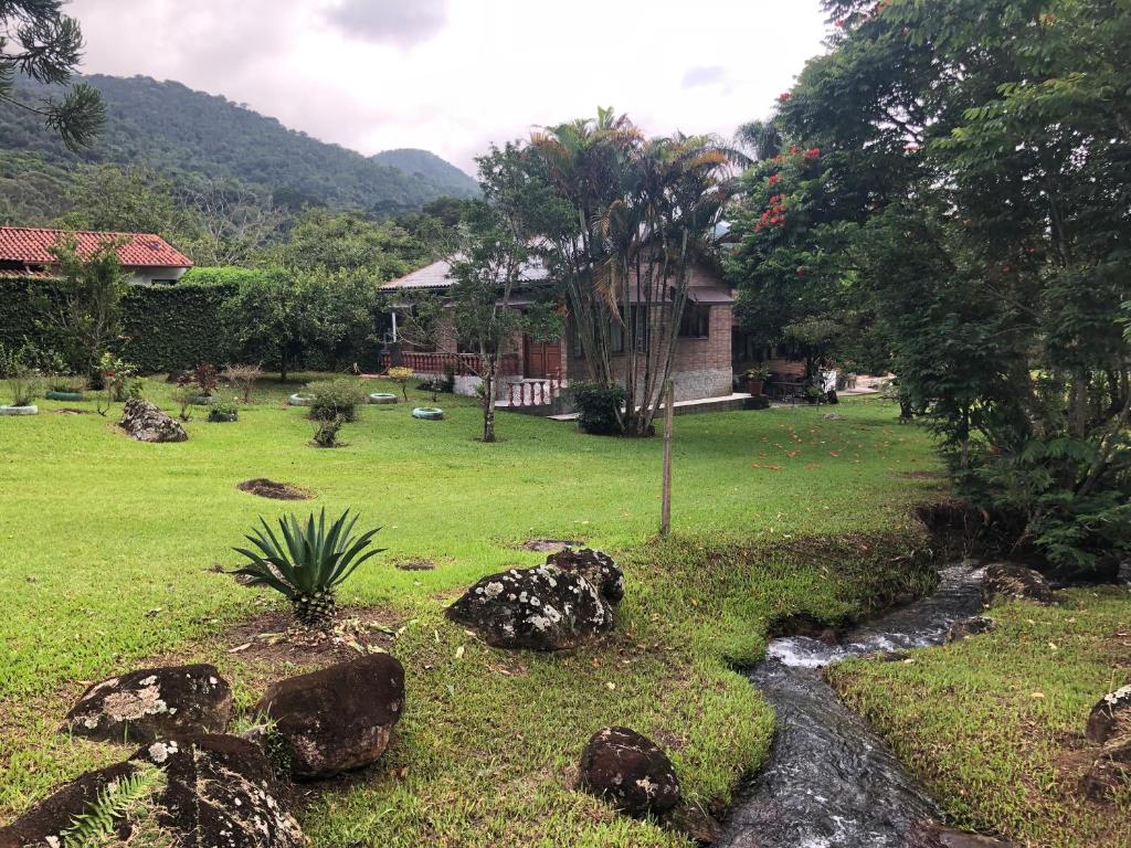 a garden with a stream in front of a house at Sítio Solar di Stella in Itatiaia