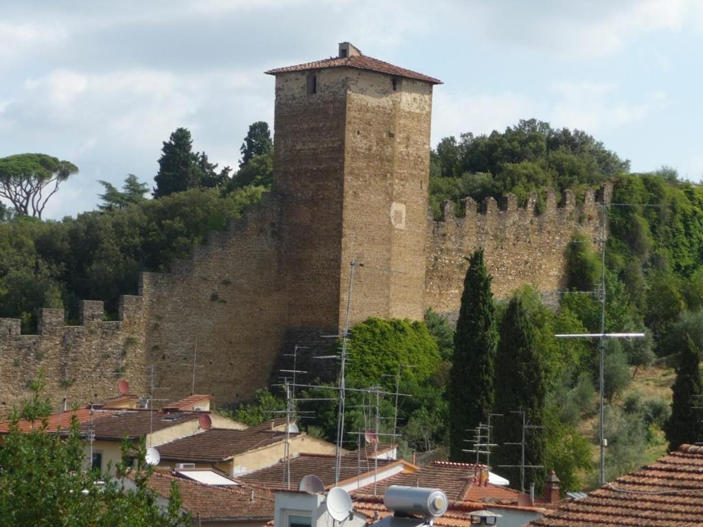 un grand bâtiment en briques avec une tour sur une colline dans l'établissement Appartamento del Bobolino, à Florence