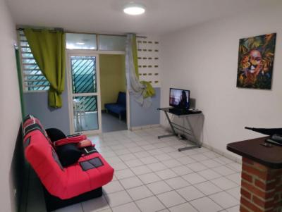 a living room with a red couch and a television at ST-Laurent Centre Confort T2 in Saint-Laurent du Maroni