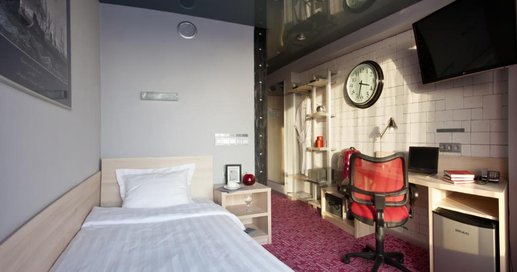 - une chambre avec un lit, un bureau et une horloge dans l'établissement Marins Park Hotel Yekaterinburg, à Iekaterinbourg