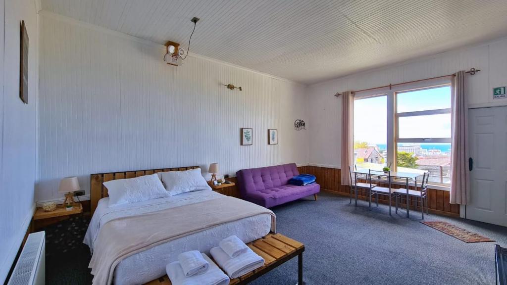 Un dormitorio con una cama grande y un sofá púrpura. en Hostal El Mesón en Punta Arenas