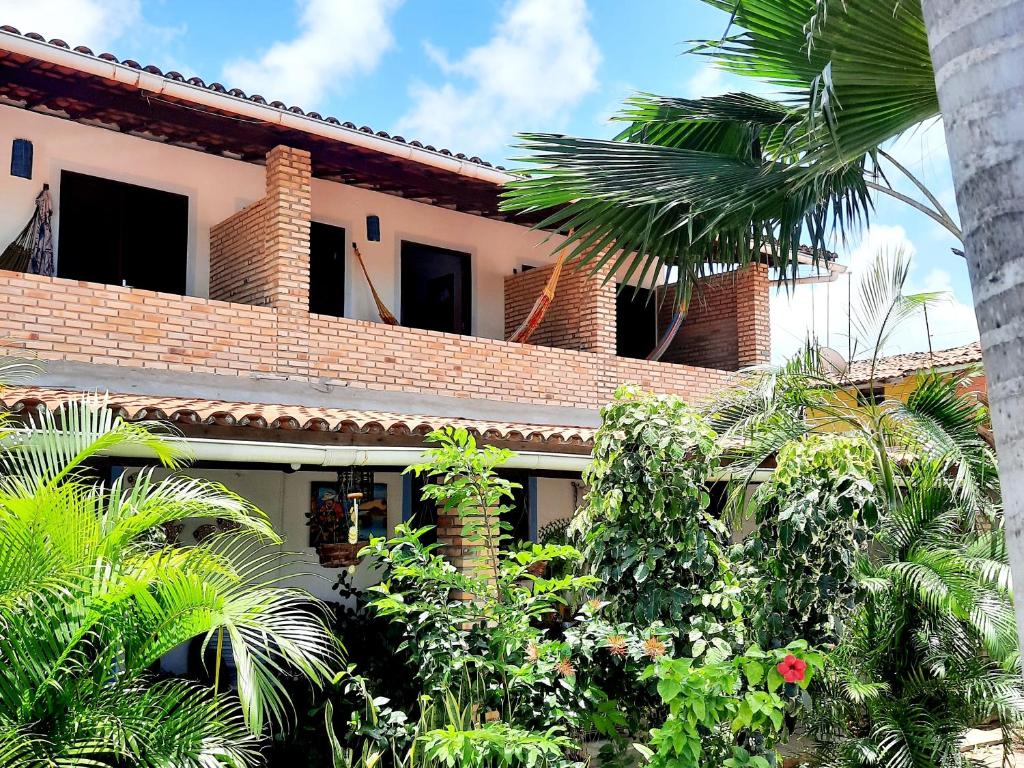 une maison avec des arbres et des plantes devant elle dans l'établissement Pousada dos Anjos Paracuru, à Paracuru