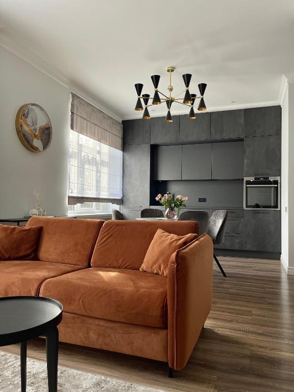 a living room with a brown couch and a kitchen at Danes23 - Self Check-in, Free Parking, Park and River View, Oldtown in Klaipėda