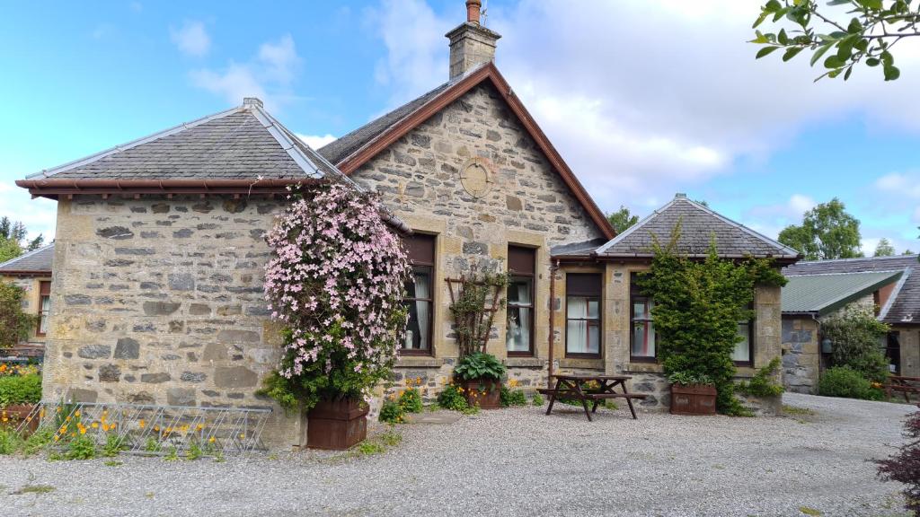 una casa di pietra con dei fiori davanti di Skye Cottage, Meadowside House, near Kingussie a Kingussie