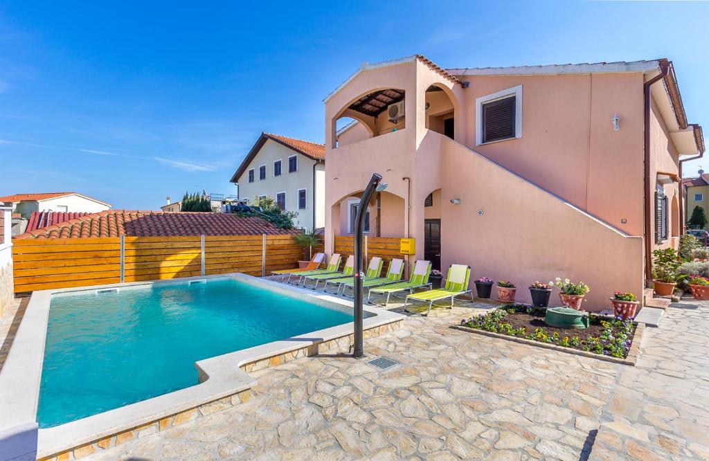 a villa with a swimming pool in front of a house at Apartments Bardak in Ližnjan