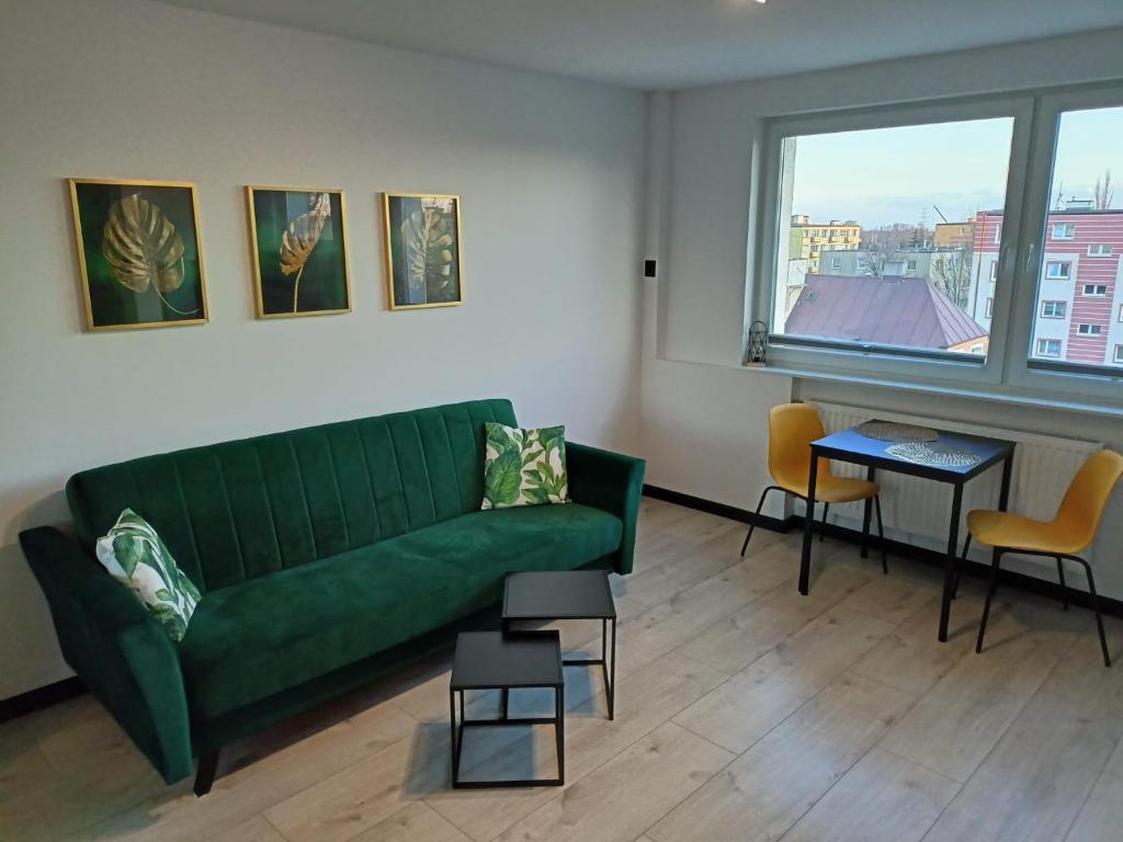 a living room with a green couch and a window at Apartament Stogi in Gdańsk