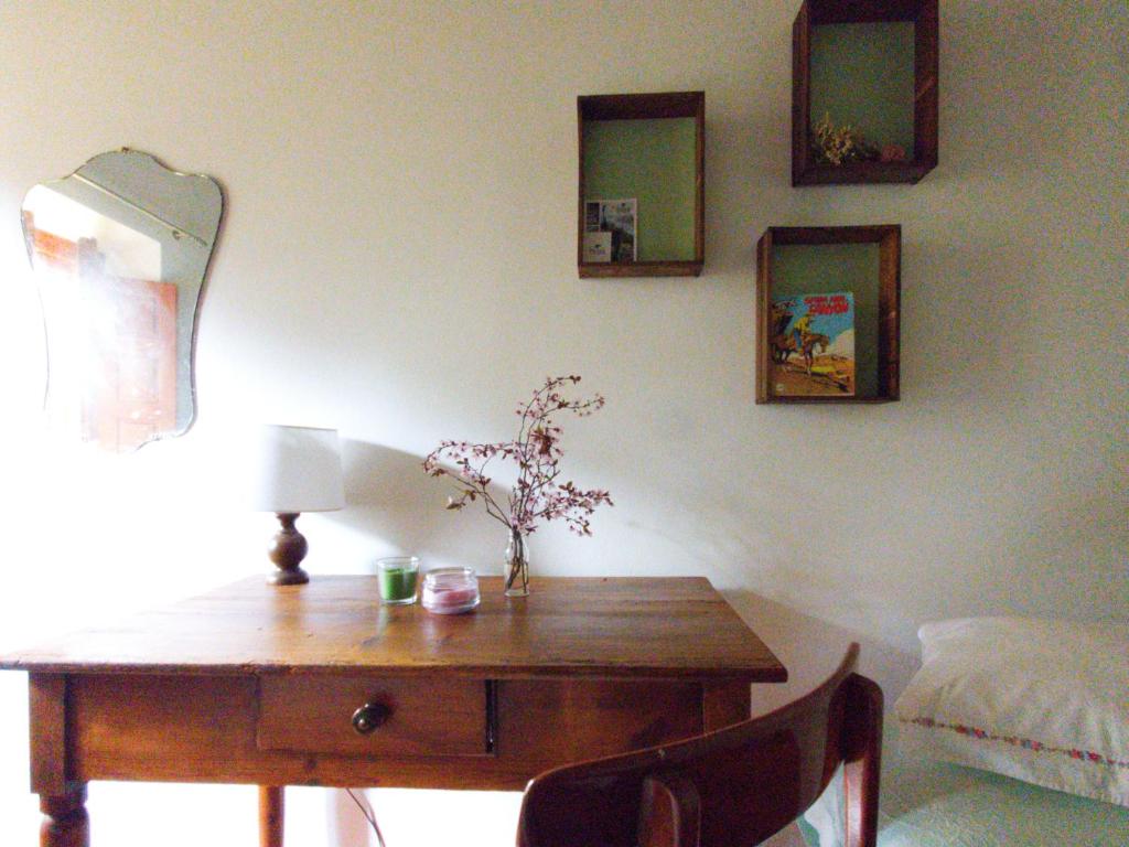una scrivania in legno con lampada e vaso di fiori di Pietra d'Acqua B&B in the woods a Buti