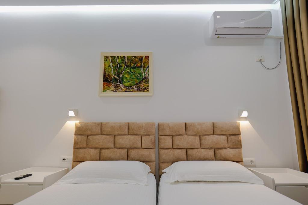two beds in a room with a picture on the wall at Vila Jon'a in Sarandë