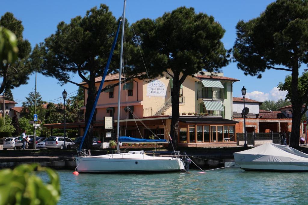 twee boten aangemeerd in een jachthaven voor een gebouw bij Albergo Trattoria Fioravante in Peschiera del Garda