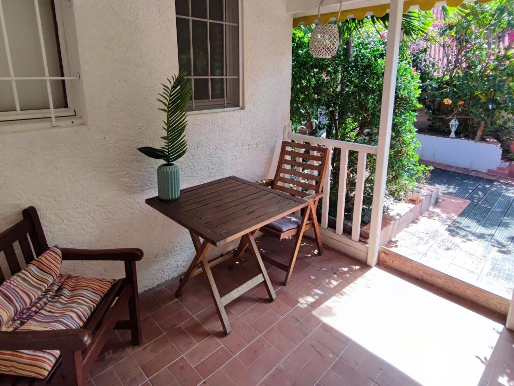 una mesa de madera y 2 sillas en el patio en Appartement entier: chambre, cuisine + terrasse au calme sur jardin., en Marigot