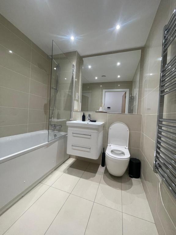 a bathroom with a toilet and a sink and a tub at Stunning 2 bed/2 bath Apartment in Warlingham