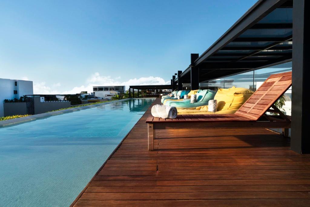 a bench sitting on a deck next to a swimming pool at Fiesta Inn Playa del Carmen in Playa del Carmen