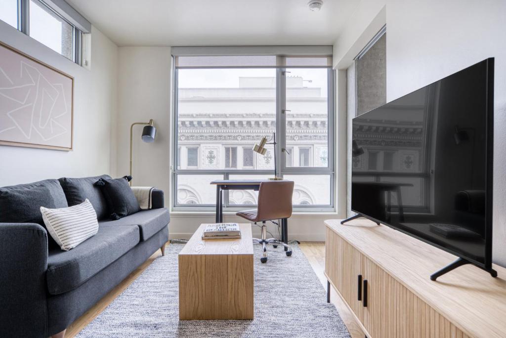 ein Wohnzimmer mit einem Sofa und einem großen TV in der Unterkunft Lower Nob Hill 1BR w Gym Roof nr bars SFO-690 in San Francisco