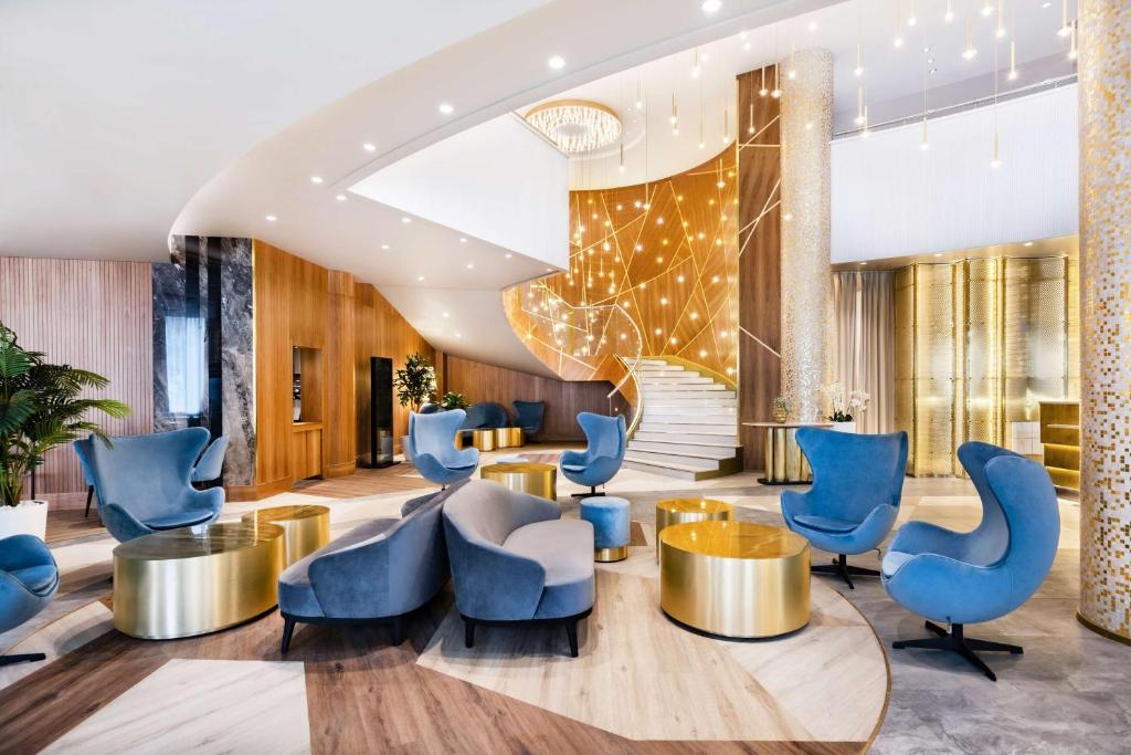 a lobby of a hotel with blue chairs and tables at Radisson Blu Belorusskaya in Moscow