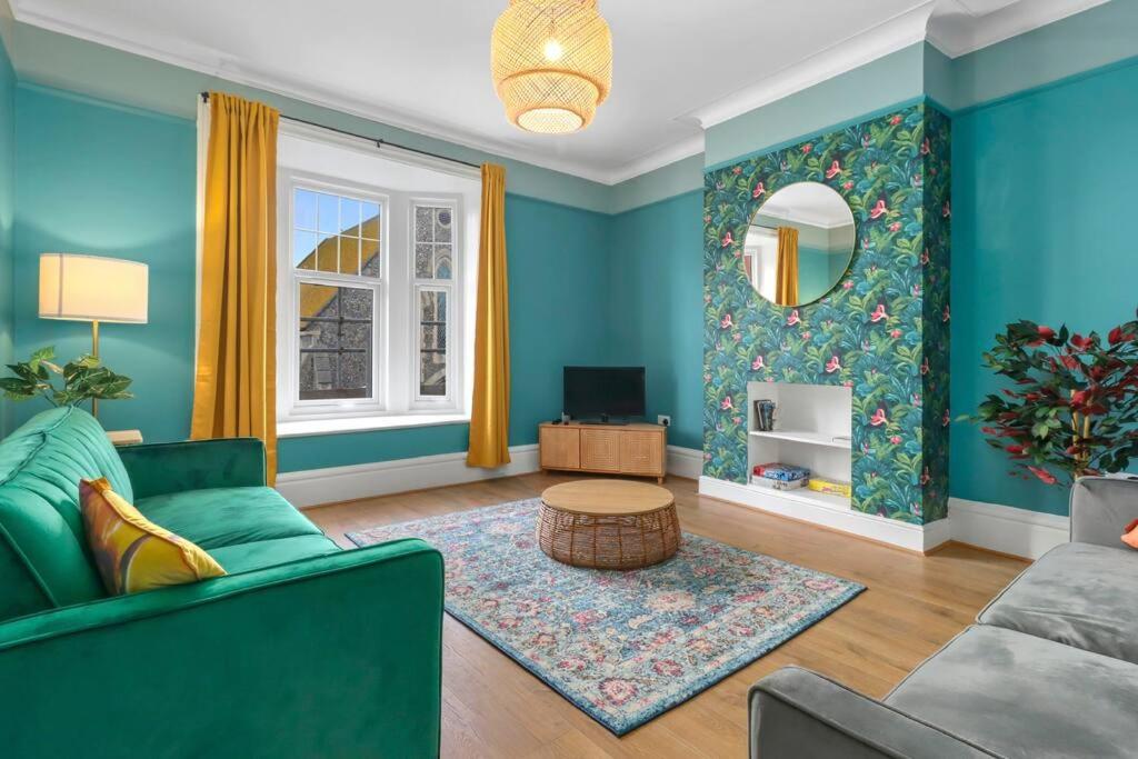 a living room with blue walls and a green couch at Clinton Place in Seaford