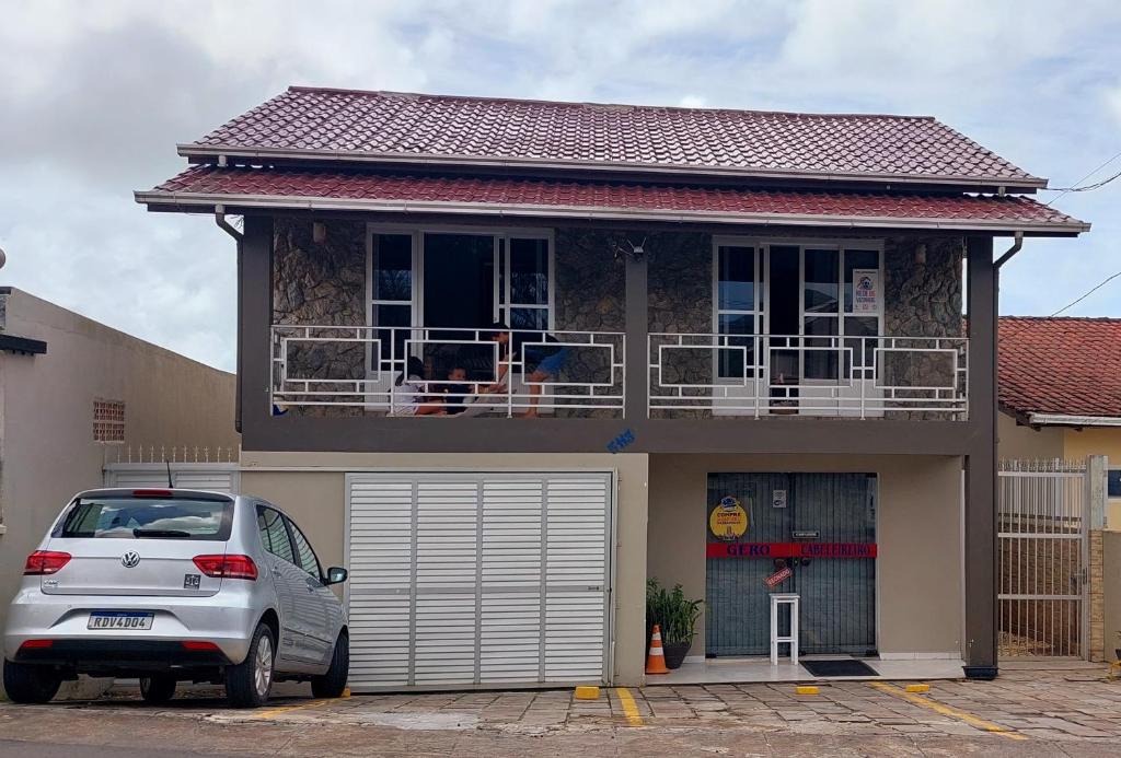 um carro estacionado em frente a uma casa com varanda em Suíte Hospedagem Ohana em Penha