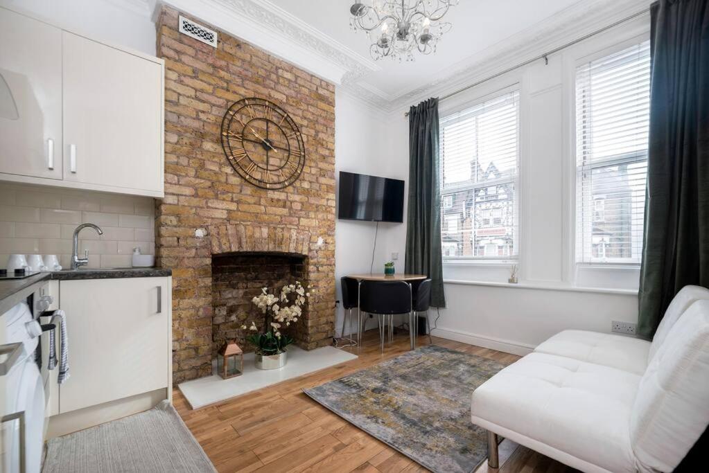 uma sala de estar com uma lareira de tijolos e um sofá branco em flat in south west London 1 min to the station em Londres