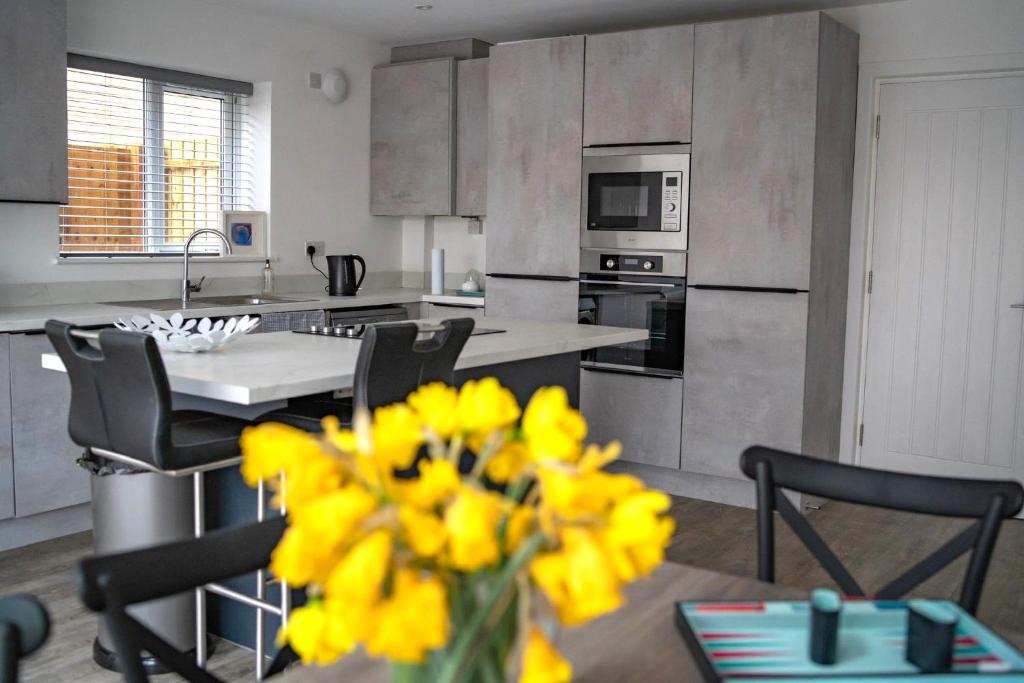 a kitchen with a table and yellow flowers in a vase at The Red House- 3 Parking Spaces Walking Distance to City Centre and Cardiff Bay 3 dbl bedrooms in Cardiff