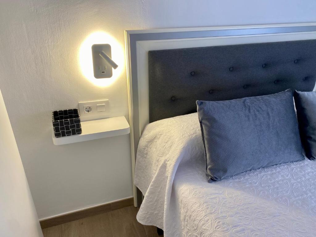 a bedroom with a bed with a blue pillow and a light at CASA GODOY in Cáceres