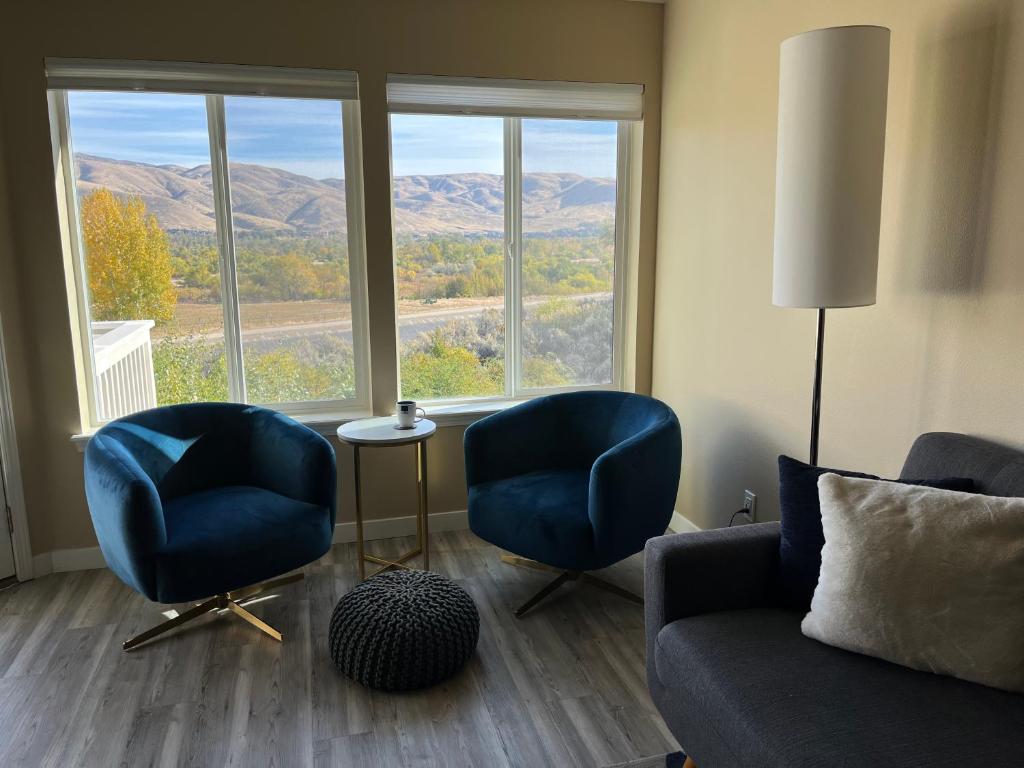 a living room with two chairs and a couch and windows at Mountain View Memories Gorgeous Views! 2 Story Pristine Condo Close to Foothills, Trails, Table Rock, Greenbelt, Bown Crossing and Barber Park in SE Boise in Boise