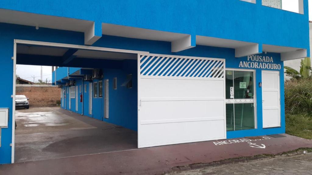a blue building with a white garage door at Pousada Ancoradouro in Cananéia