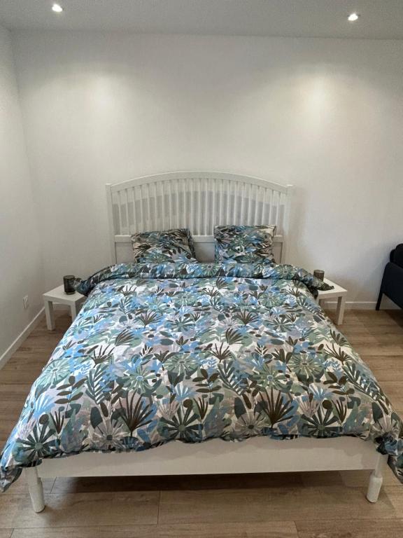 ein Bett mit einer blauen und weißen Bettdecke und Kissen in der Unterkunft Studio proche Stade de France in Saint-Denis